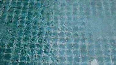 Yağmur damlaları havuzun yüzeyinde dalgalanmalar yaratır, doğal ışıklandırma altında sakin ve dokulu bir su deseni sergilerler.