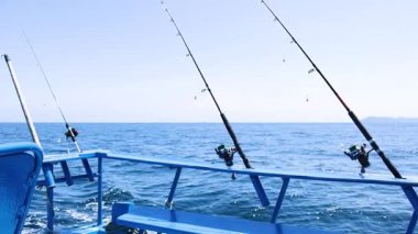 Tayland, Phuket 'te bir teknede balık tutma çubukları. Parlak gün ışığında sakin okyanus manzaralarını yakalıyorlar.