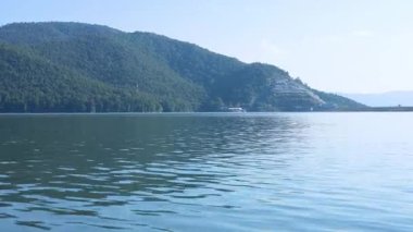 Bir tekne sakin ve manzaralı bir göl boyunca yol alır.