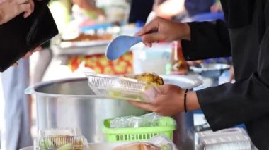 Tezgahtaki konteynırlara yemek servisi yapan kişi