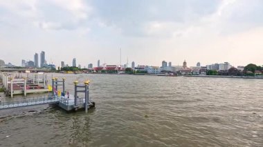 Chao Phraya Nehri 'nin sakin manzarası. Bangkok' un ufuk çizgisi yumuşak gün ışığında kentsel ve doğal elementleri gözler önüne seriyor.