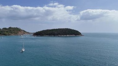 İnsansız hava aracı görüntüleri, Phuket, Tayland yakınlarındaki sakin okyanus manzaralarını ve tekneleri yumuşak kamera hareketleriyle açık gökyüzünün altında yakalıyor.