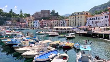 Dalgalı bir sahil limanına yanaşmış tekneler.