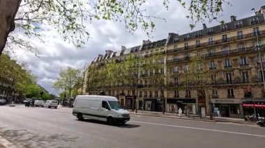 Minibüsler ve arabalar Paris caddesinde ilerliyor.