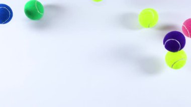 Beyaz bir yüzeyde birden fazla tenis topu zıplıyor.
