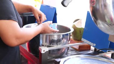 Parlak bir mutfak ortamında metal bir çömlek kullanan biri tatlı hazırlar. Bu süreç dikkatli karıştırma ve dikkat gerektirir.