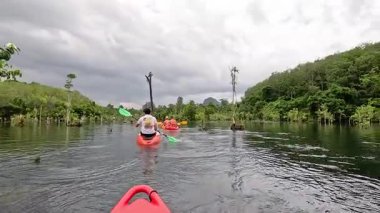 Kayakçılar yemyeşil sularla çevrili sakin sularda gezinirler.