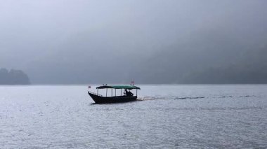 Sakin, sisli bir göl üzerinde bir tekne durmadan hareket eder..