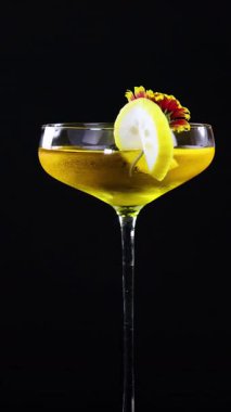 Siyah arka planda canlı çiçekli limon ekşi bir kokteyl. Zarafet ve incelik sergiliyor.