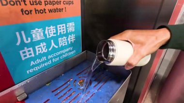 Person pours hot water despite cautionary sign