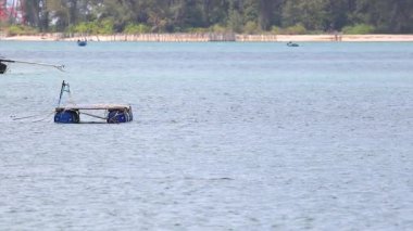 A boat navigates calm waters near Sarasin Bridge, Phuket, under clear skies. The serene environment highlights the tranquil coastal scenery