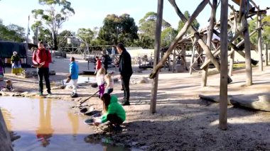 Visitors engage in gold panning at Sovereign Hill, Ballarat, under bright daylight, capturing a historical experience in a lively setting