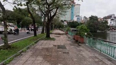 Vehicles and pedestrians near lake in Hanoi