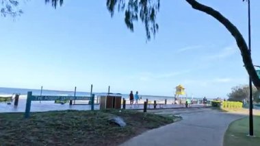 İnsanlar kıyı parkında güneşli bir günün tadını çıkarıyorlar.