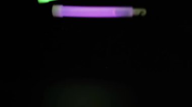 Glow sticks falling and scattering on a dark surface