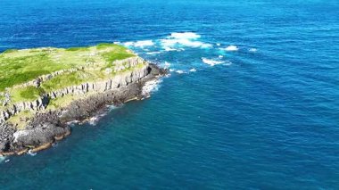 Dalgalar altıgen volkanik kaya oluşumlarına çarpar.