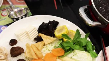 Cooking ingredients in a hotpot with chopsticks