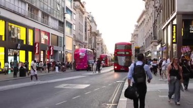 People walking, red bus, and shops in London