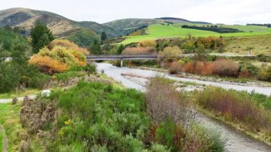 Huzurlu bir nehir, Yeni Zelanda 'nın Tekapo Gölü' ndeki bulutlu gökyüzü altında yemyeşil ve yuvarlanan tepeler boyunca kıvrılır.