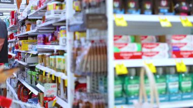 Alışveriş arabası olan bir kadın Avustralya 'nın Gold Coast şehrinde bir süpermarket koridorunda geziniyor. Parlak ışık ve canlı renkler canlı bir atmosfer yaratır.