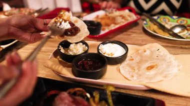 Lokantalar sıcak aydınlatılmış bir Meksika restoranında çeşitli malzemelerle tlayudaların tadını çıkarıyorlar.