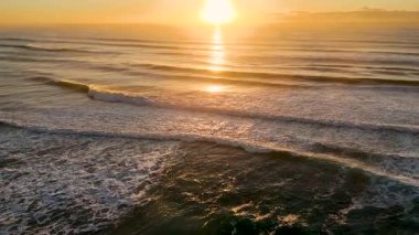 Okyanus dalgalarına yansıyan altın gün doğumu