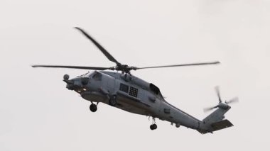 Bir helikopter Geelong 'daki Avalon Hava Gösterisi' nde bulutlu bir gökyüzüne karşı dinamik hava manevraları gerçekleştiriyor ve çeviklik ve hassasiyet gösteriyor.