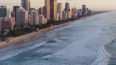 Güneş doğarken Altın Sahil 'in ufuk çizgisini ve okyanus dalgalarını görüntüleyen hava görüntüleri, kentsel mimariyi ve doğal güzelliği vurguluyor.