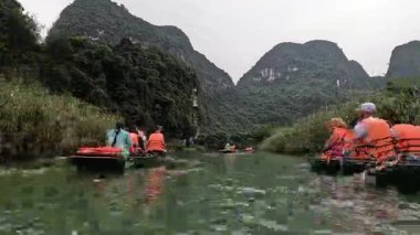 Turistler sakin bir manzarada kürek çekiyorlar.