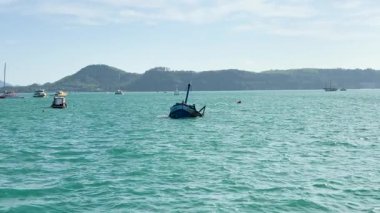 Chalong Körfezi, Phuket 'te açık gökyüzünün altında tekneler ve uzak dağlarla sakin bir okyanus manzarası. Huzurlu ve resim gibi bir ortam.