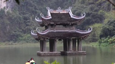 Geleneksel pavyonun yanında kürek çeken turistler