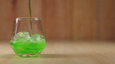 Yeşil sıvı buzla bardağa döküldü.