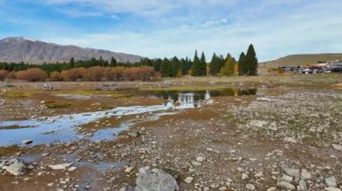 İnsansız hava aracı, Tekapo Gölü 'nün sakin manzarasını sonbahar renkleriyle, suyu ve açık gökyüzünün altındaki uzak dağları yansıtıyor.