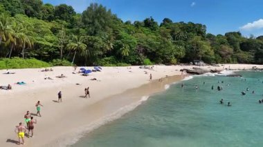 İnsansız hava aracı görüntüleri Phuket, Tayland 'da canlı bir kumsal görüntüsü yakalıyor. Yeşilliklerin ortasında güneşlenip denizin tadını çıkaran insanları gösteriyor.
