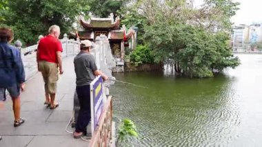 Tapınak ve göl yakınlarındaki köprüde yürüyen insanlar