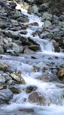 Sabit bir gün ışığı ve hareketli su hareketini yakalayan sabit bir kamerayla kayaların üzerindeki temiz dağ akıntıları doğal bir ortamda.