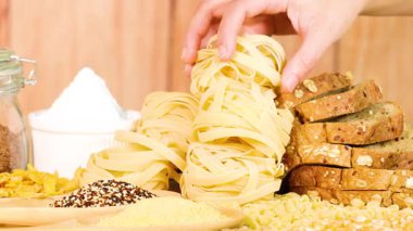 Bir el, tagliatelle makarnasını parlak ve sıcak bir ortamda ekmek ve tahıl vitrininden seçer.