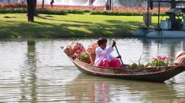 Bangkok parkında çiçeklerle kürek çeken bir adam.