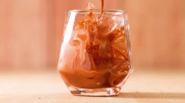 Thai çayı buzlu bardağa dökülüyor.