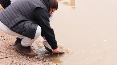 Çamurlu suda altın arayan kişi