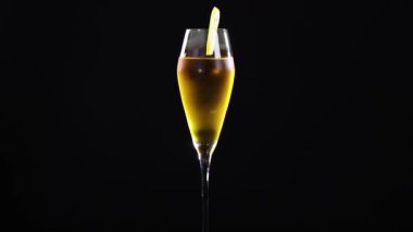 Limonlu bir bardakta limon ekşili kokteyl, siyah arka planda ayarlanmış, zarif bir sadelik sergiliyor.