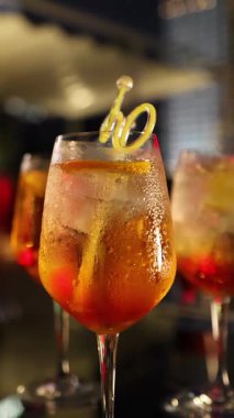 Bir grup genç yetişkin şık bir gece partisinde kokteyllerin keyfini çıkarırken, kamera odak noktasını içkiden neşeli sohbete ve kahkahaya çeviriyor.