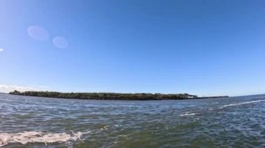 Dalgalar ve kıyı şeridi açık mavi gökyüzünün altında