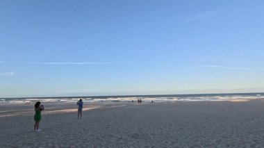 İnsanlar kumsalda güneşli bir günün tadını çıkarıyorlar.