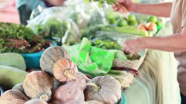 Canlı bir pazarda sebze seçen eller.