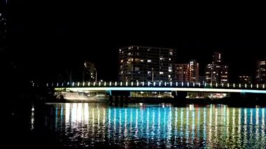 Şehir ışıkları geceleri suyu yansıtıyor.