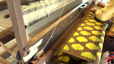 Zanaatkar elle karmaşık ipek desenler örüyor.