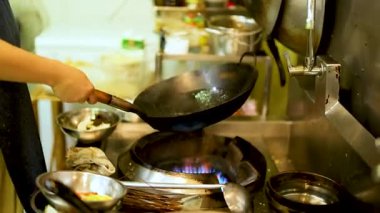 Aşçı ustalıkla mutfakta tavayla yemek pişiriyor.