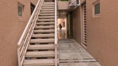 Tuğladan bir binanın ara sokağında merdivenleri tırmanan biri.