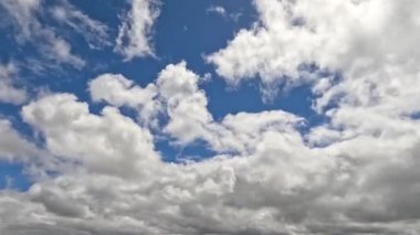 Kümülüs bulutları mavi gökyüzünde hareket ediyor